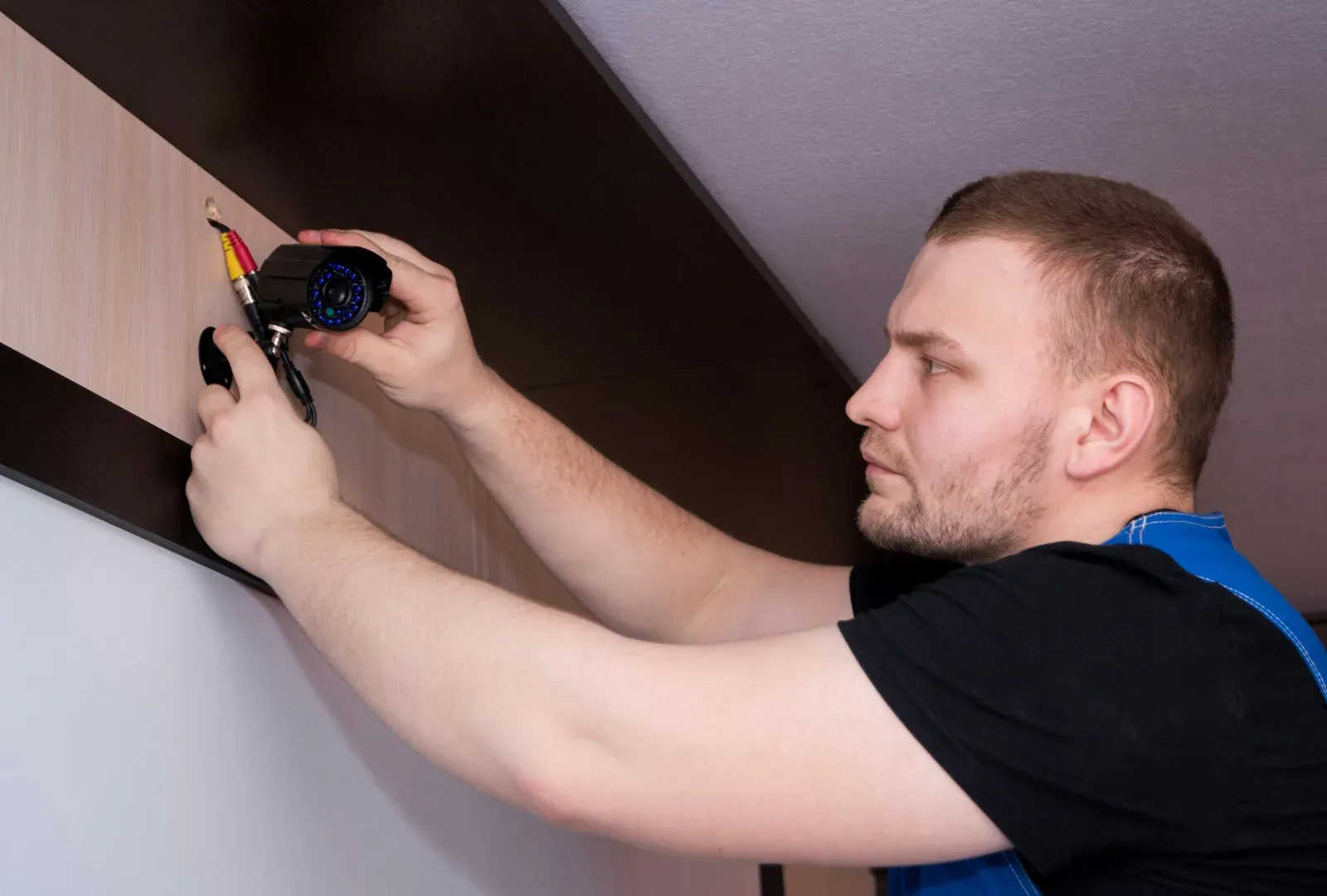 Electrician fitting a light fitting to a ceiling beam