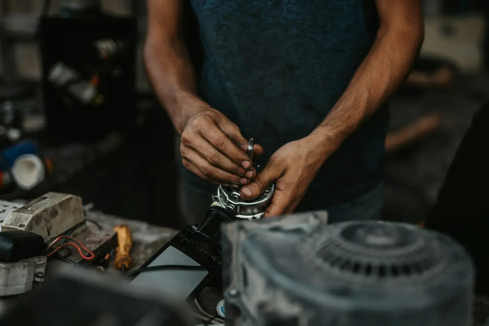 Hands working on the wiring of an electric motor on a workbench